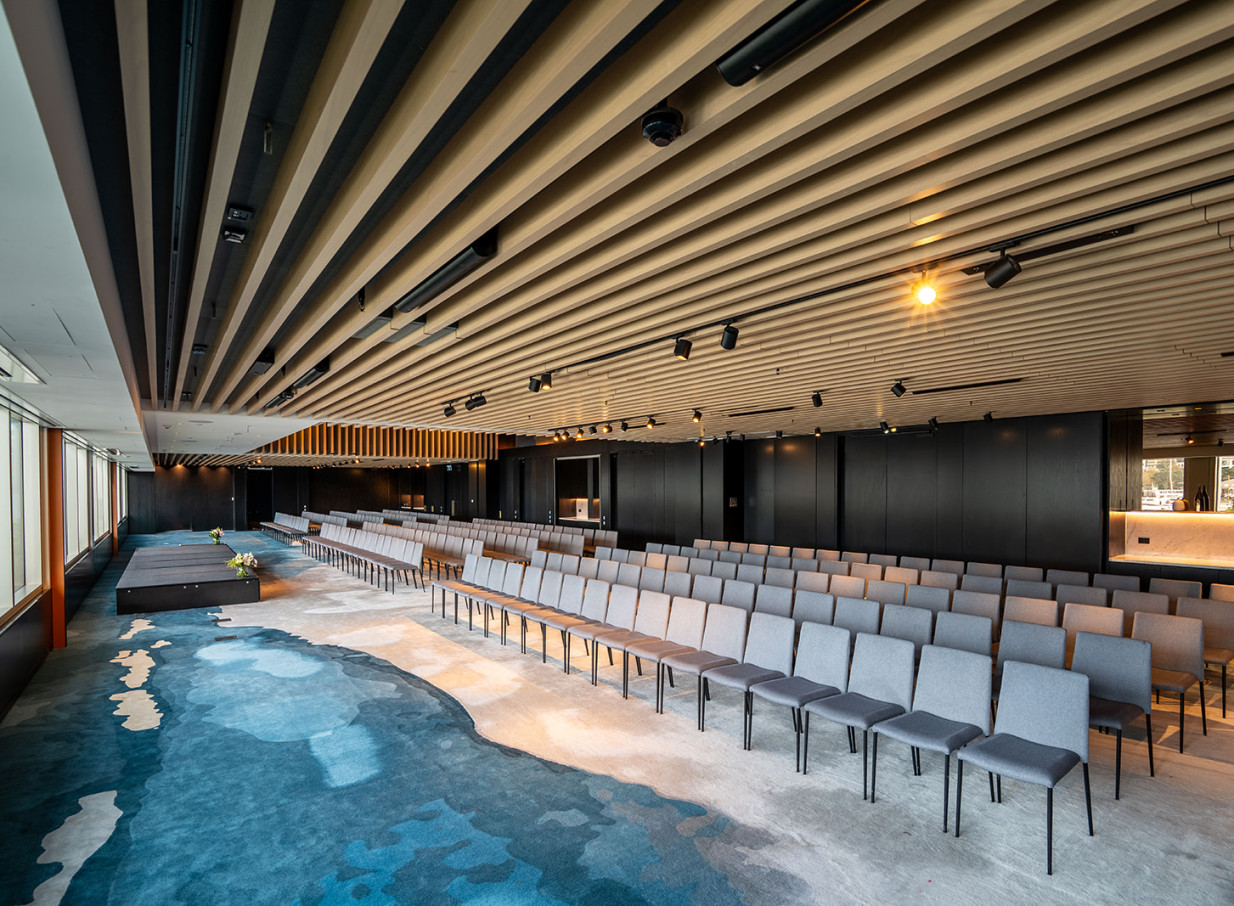 A contemporary event space at Park Hyatt Auckland, with its timber-slatted ceiling, abstract blue carpet, and rows of chairs, embodies local design.