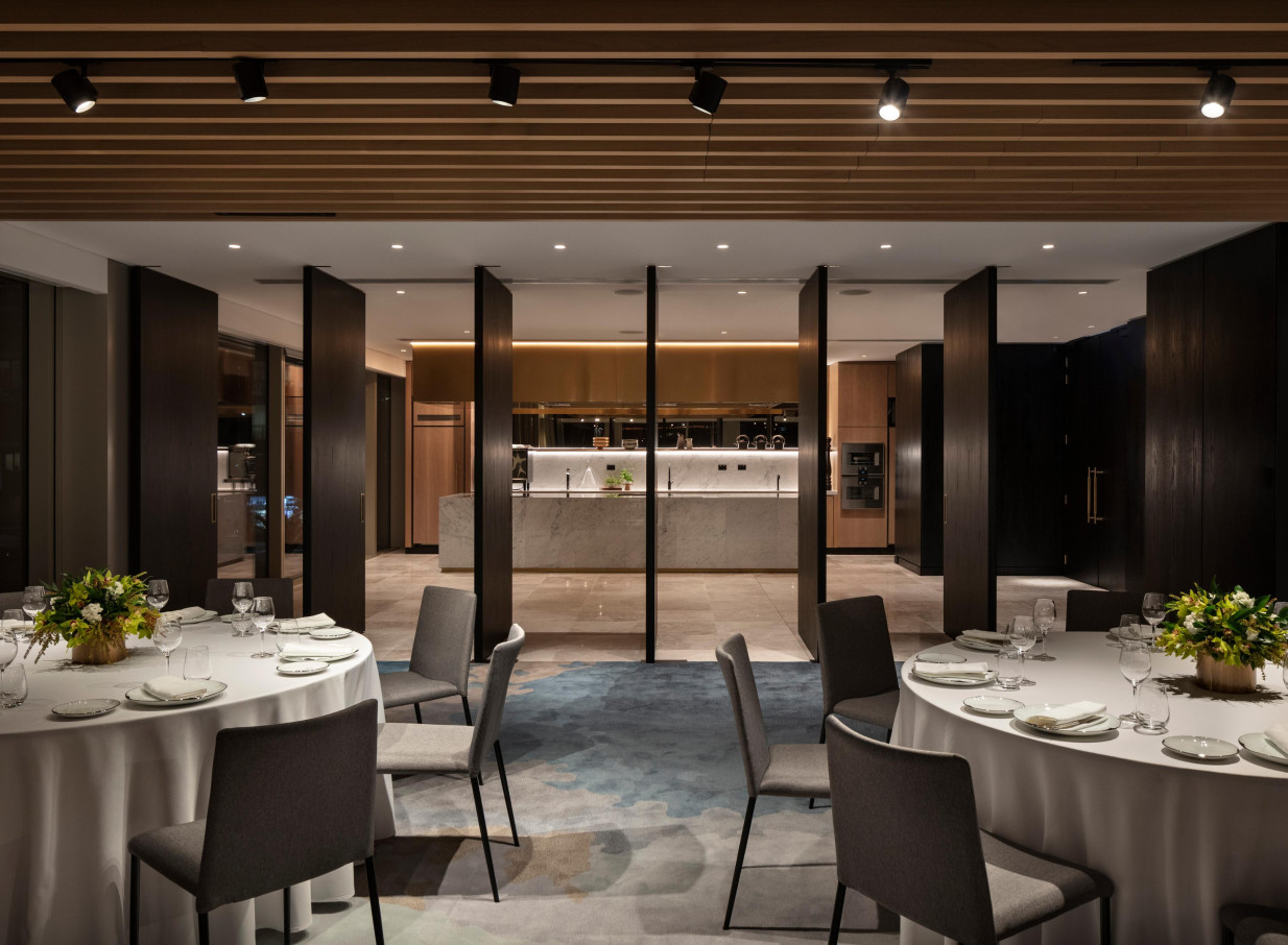 A modern private dining room featuring an open kitchen and natural timber and stone accents at the luxurious Park Hyatt Auckland.