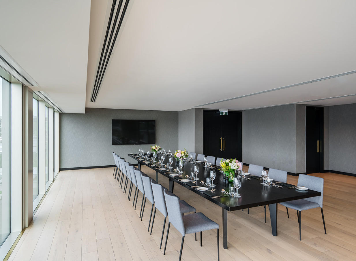 A modern minimalist event space with warm natural finishes and expansive windows at Park Hyatt Auckland.