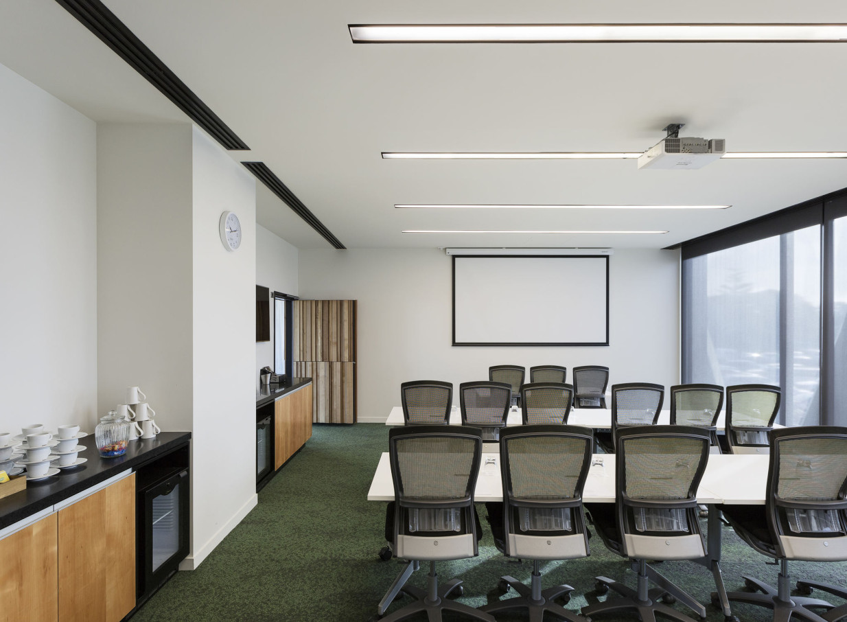 A contemporary meeting room at Novotel Auckland Airport, with a projector screen and a convenient refreshment counter.