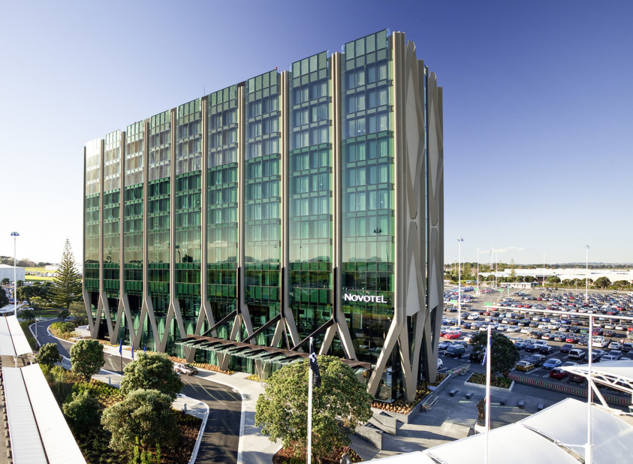 The Novotel Auckland Airport showcases a modern exterior with green glass and striking V-columns, inspired by New Zealand's heritage.
