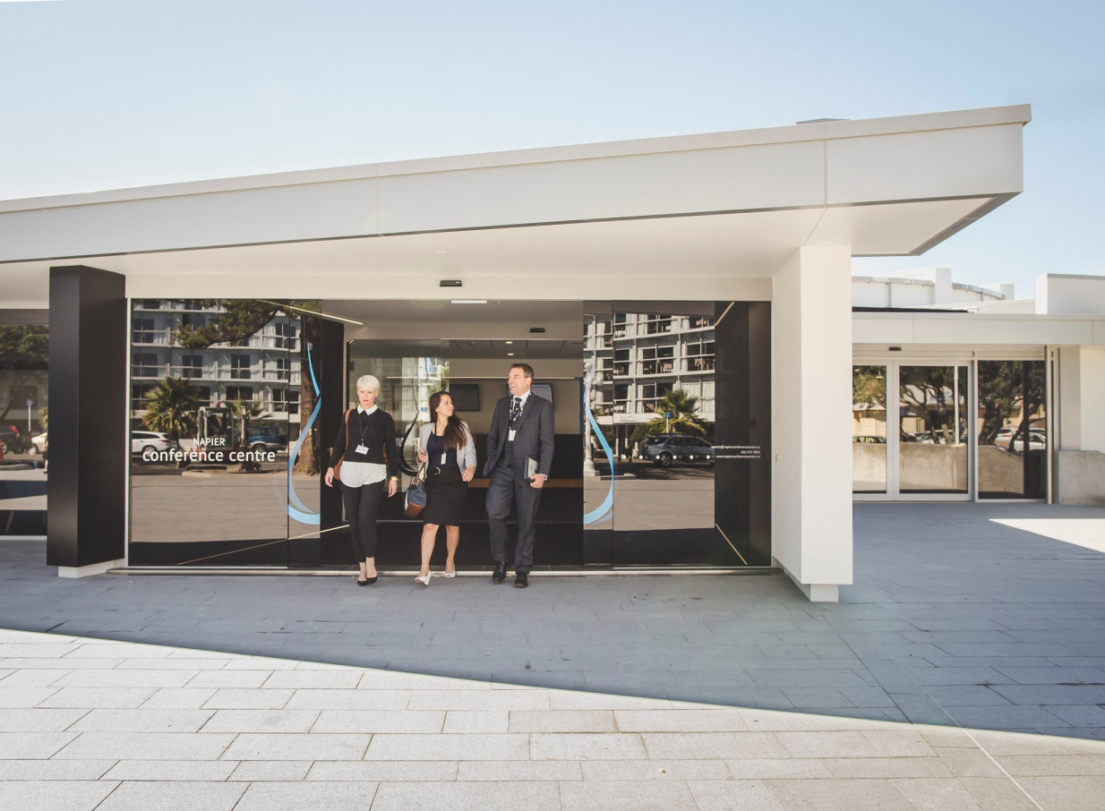 Three people exit the stylish, modern main entrance of Napier Conferences & Events in Hawke's Bay.