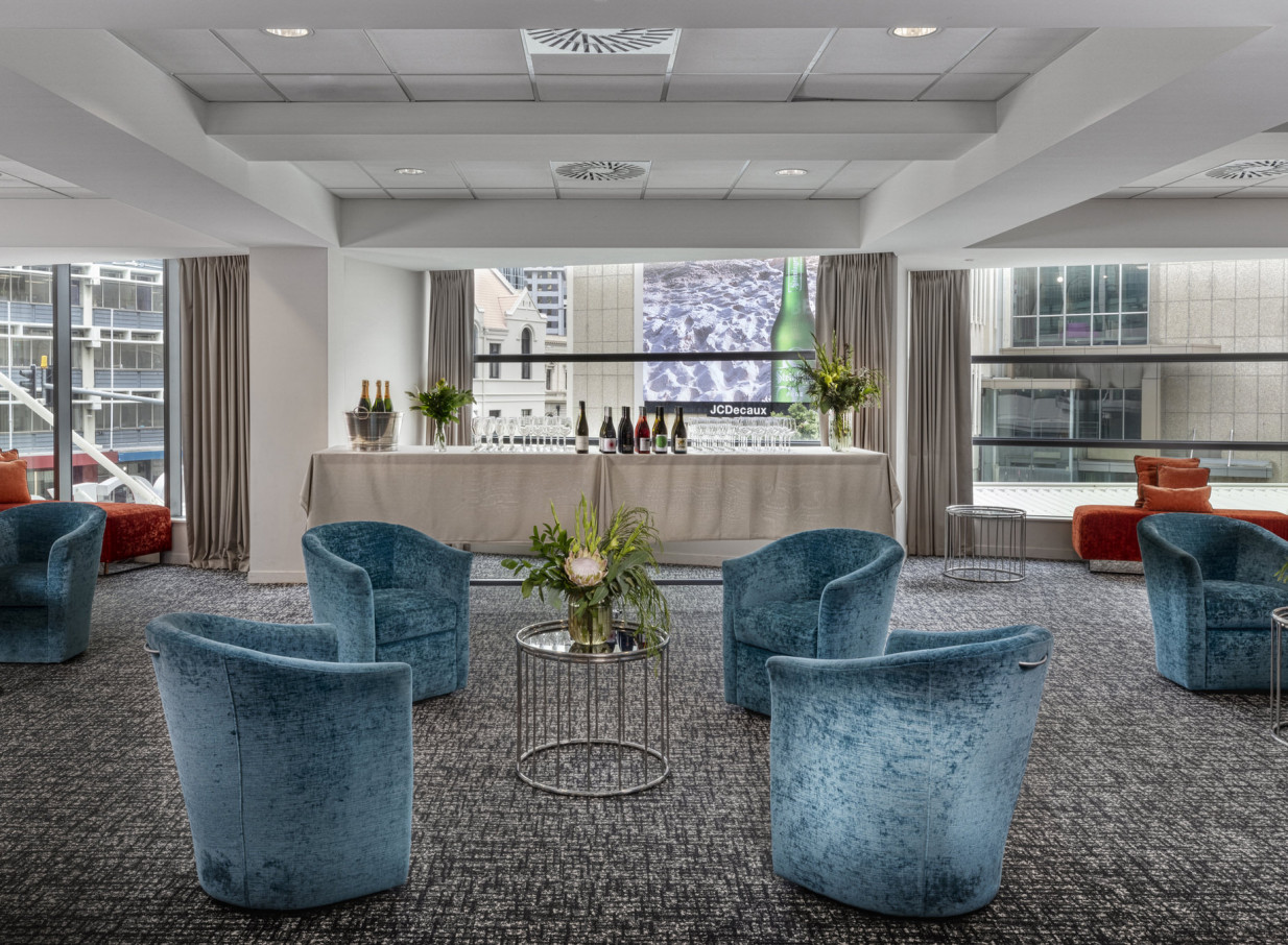 Rydges Wellington offers a contemporary pre-function lounge with a bar setup and plush teal seating, overlooking Wellington city.