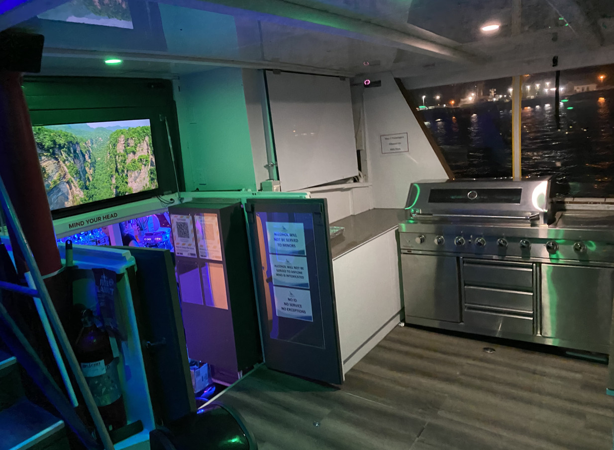 Ocean Groove Cruises, Auckland, offers a stylish private charter boat interior with an illuminated bar and BBQ grill for events.