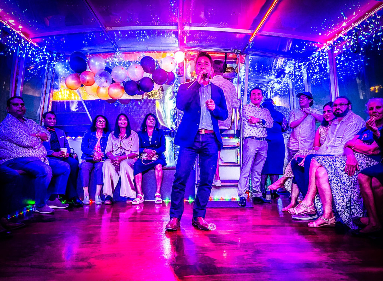 Guests enjoy a vibrant karaoke event on an Ocean Groove Cruises party boat in Auckland, featuring colorful lights and balloons.