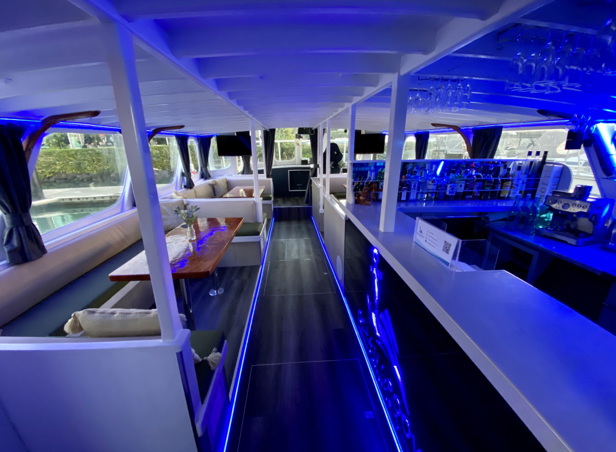 The modern, Mediterranean-inspired interior of Ocean Groove Cruises in Auckland features a bar and blue-lit lounge seating.