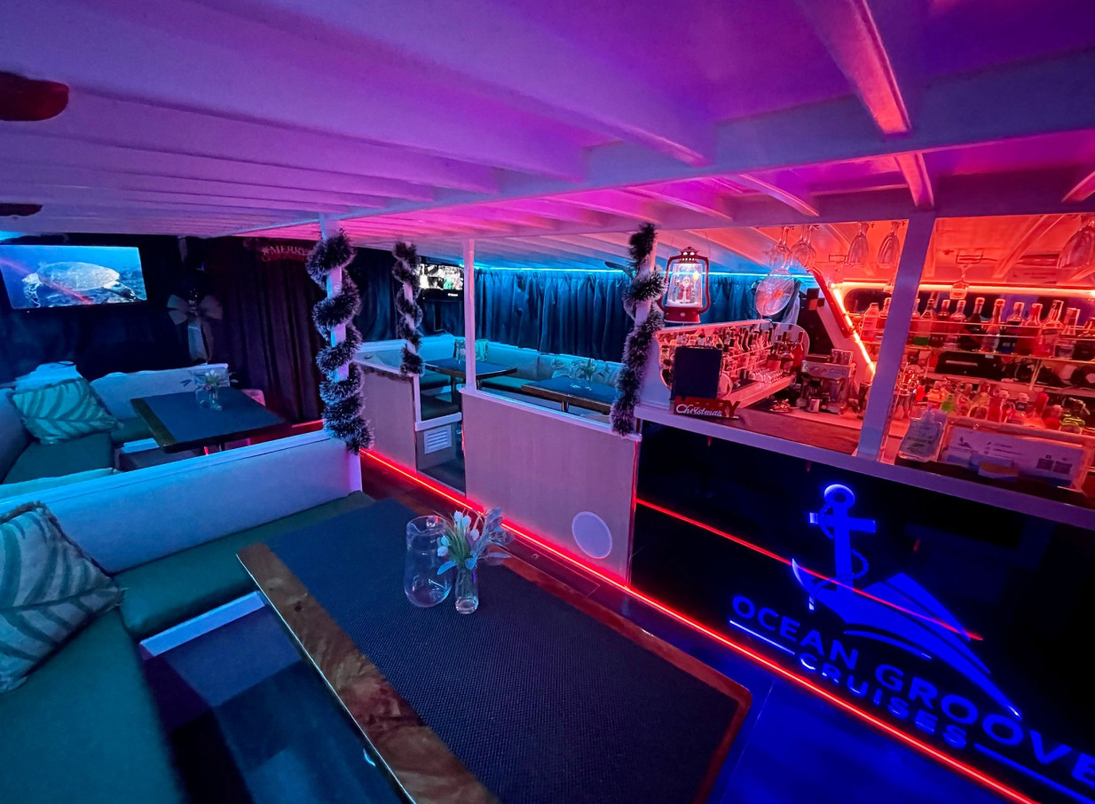 Ocean Groove Cruises in Auckland features a vibrant party boat lounge with colorful LED lighting and a bar.