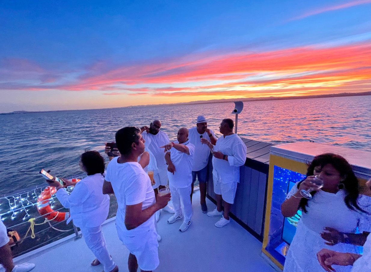 Guests enjoy a vibrant sunset party on an Ocean Groove Cruises charter boat in Auckland.
