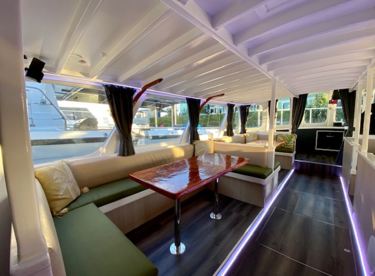 The stylish, modern charter boat interior of Ocean Groove Cruises, Auckland, offers a comfortable lounge with bench seating and ambient lighting.