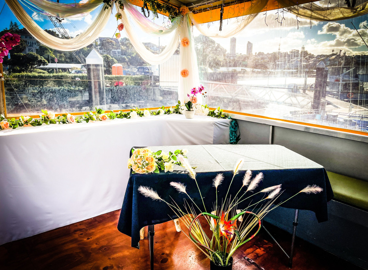 An elegantly decorated contemporary event space aboard Ocean Groove Cruises' charter vessel in Auckland, offering scenic harbor views.