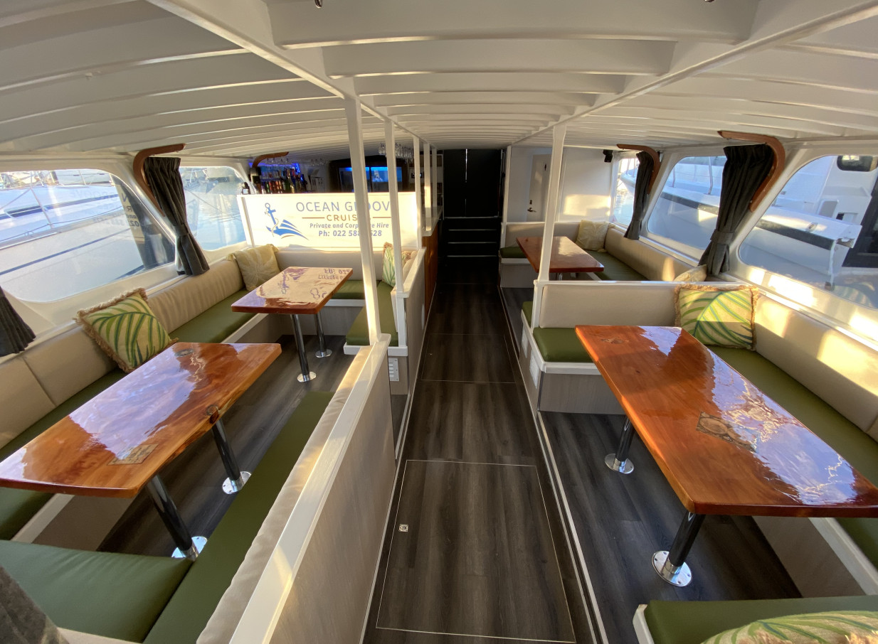 Ocean Groove Cruises in Auckland presents a stylish, modern Mediterranean-inspired interior lounge with green and beige booth seating.