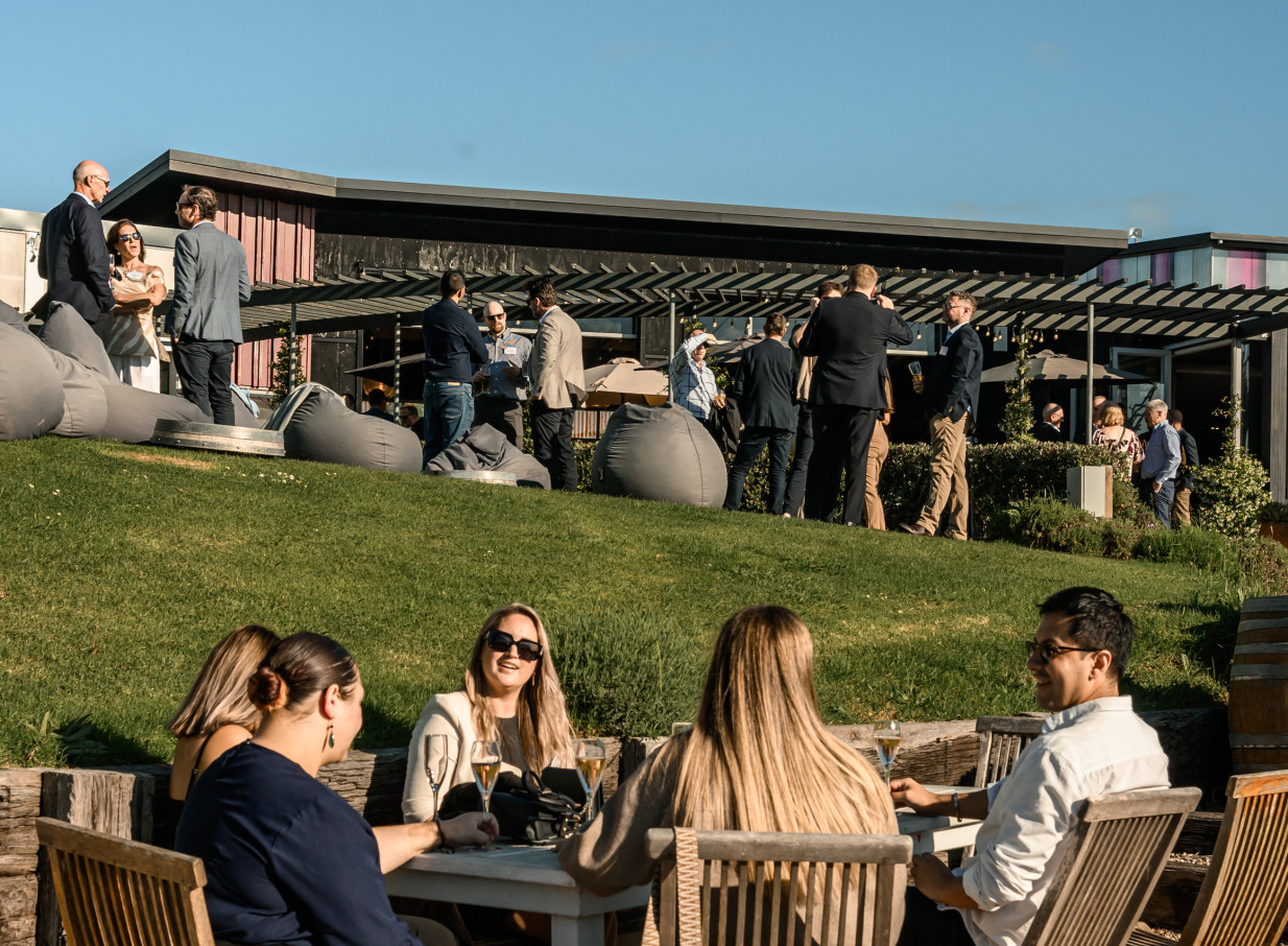 Guests enjoy an outdoor social event on the expansive lawns of Batch Winery, a modern vineyard setting on Waiheke Island.