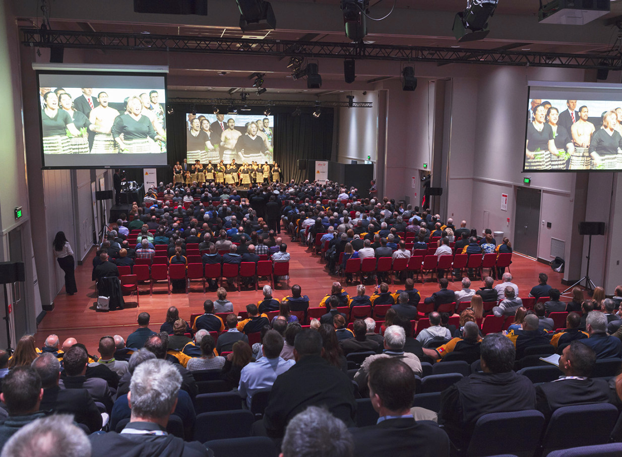 A large conference in Shed 6, Wellington's flexible, pillarless venue, showcases a stage with performers and projection screens.