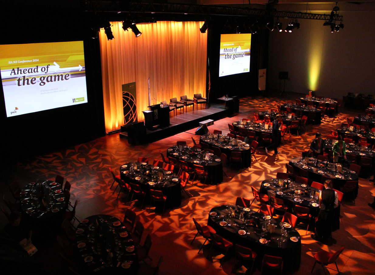 A contemporary banquet setup in Shed 6, Wellington's versatile, pillar-less event space, featuring a stage and screens.