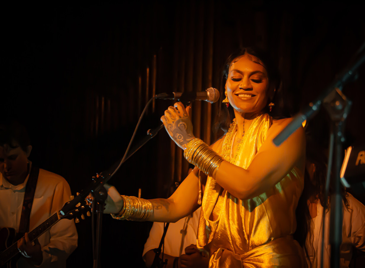 A singer performs under warm lighting in the wooden Gothic Revival interior of Old St Paul's, Wellington.