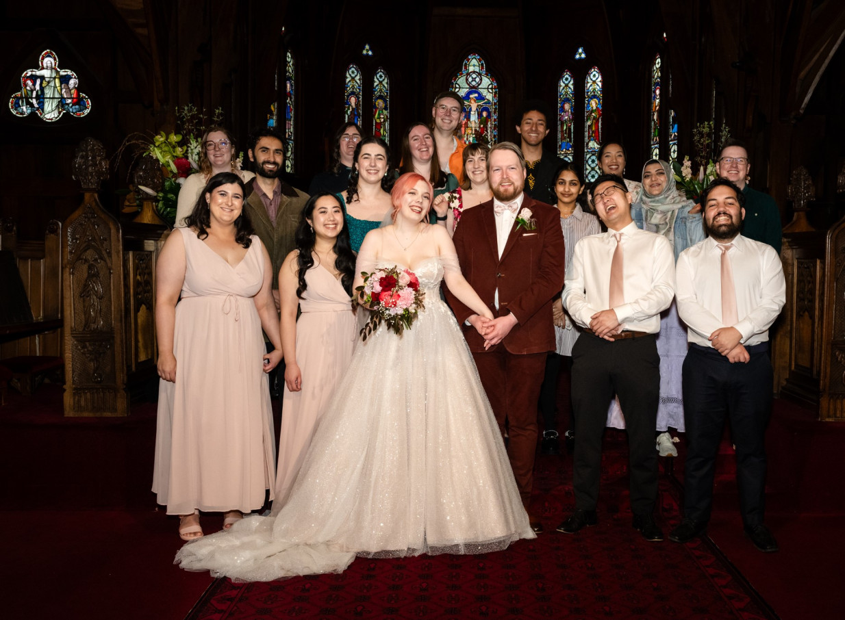 A wedding group celebrates inside Old St Paul's in Wellington, a Gothic Revival church showcasing timber architecture and stained-glass windows.