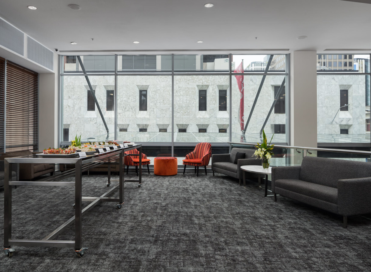 A contemporary lounge space with a buffet setup and comfortable seating, bathed in natural light at Rydges Auckland.