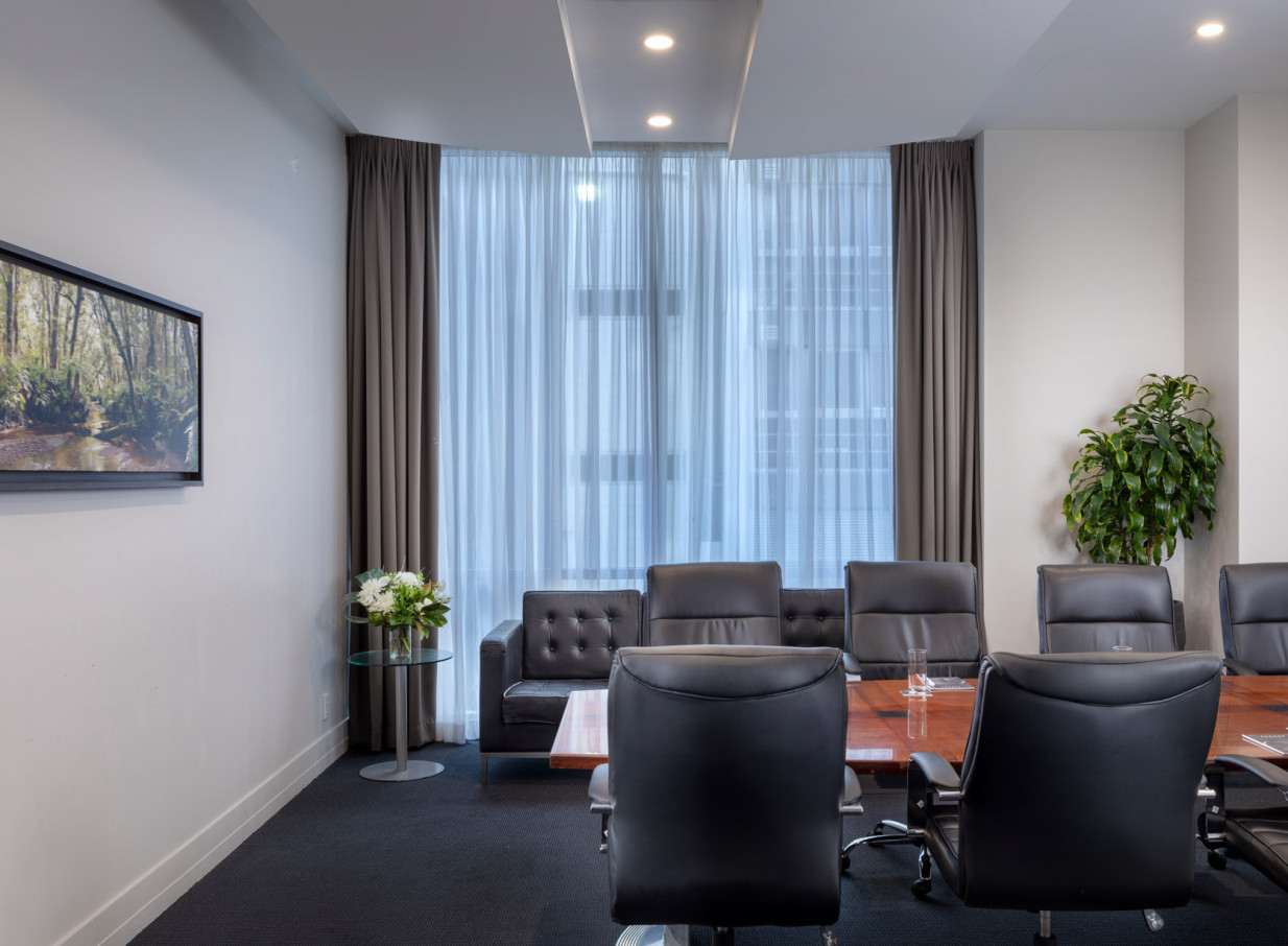 A contemporary meeting room at Rydges Auckland, featuring a large boardroom table, executive chairs, and ample natural light.