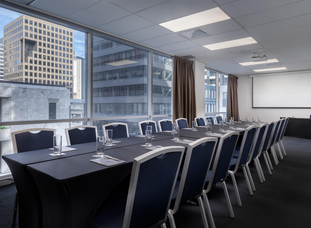 A contemporary meeting room at Rydges Auckland with floor-to-ceiling windows offering city views.