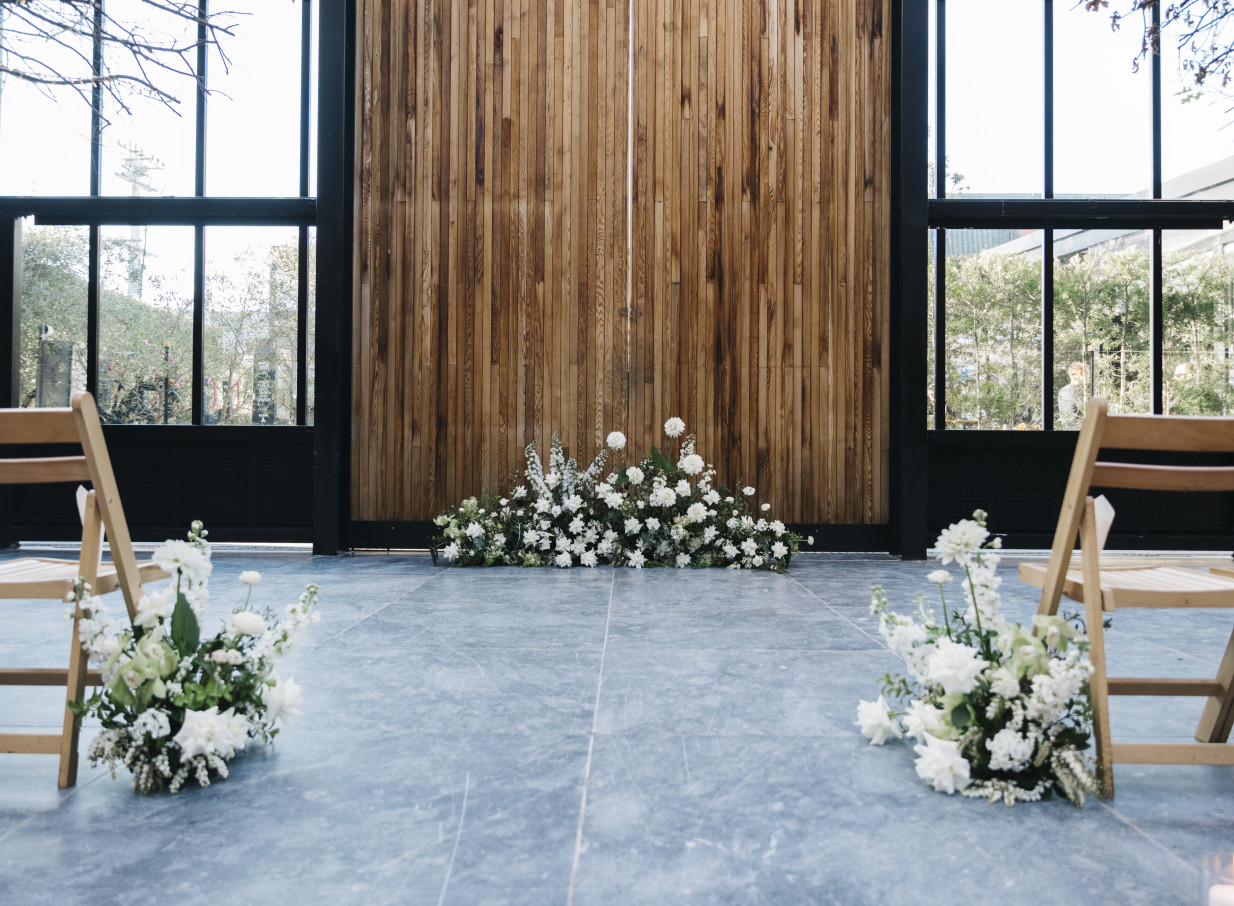 A wedding ceremony setup in the industrial-chic, glass-walled Glasshouse Morningside in Auckland.