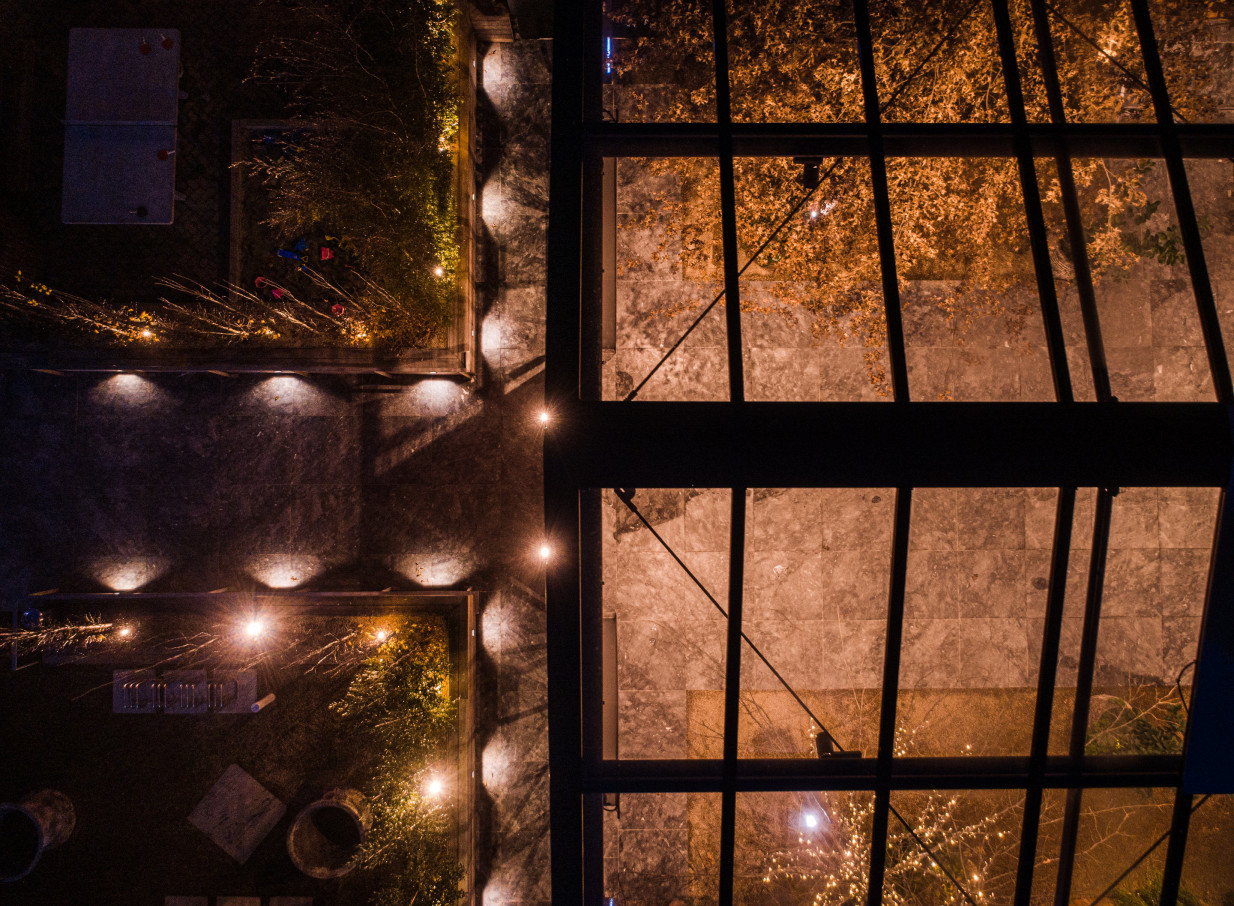 Glasshouse Morningside, Auckland, presents its illuminated outdoor garden and modern glass-roofed event space at night.