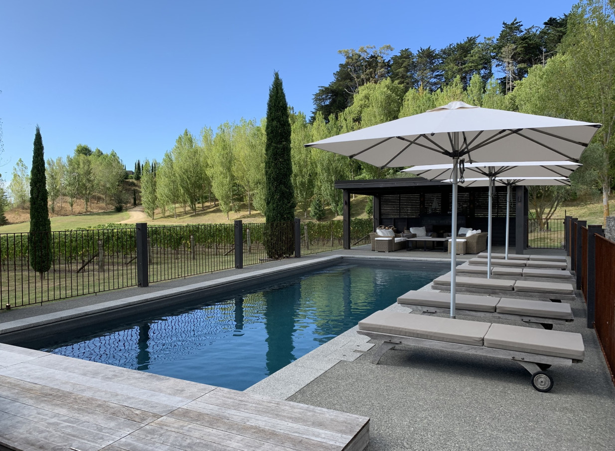 The River House, Hawke's Bay, offers a Mediterranean-inspired outdoor pool and lounge area overlooking vineyards.