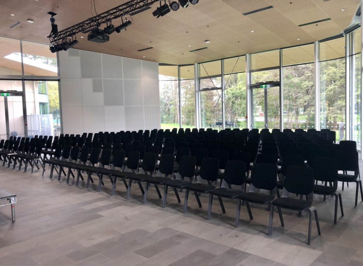 A bright, architecturally designed Haere-Roa event space in Christchurch, featuring rows of chairs and large windows overlooking greenery.