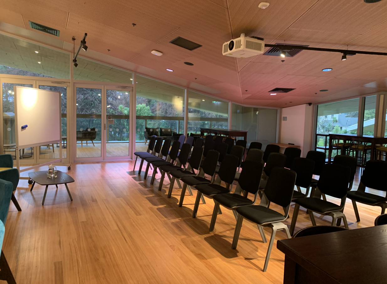 A modern, light-filled conference room at Haere-Roa, Christchurch, with an angled ceiling, projector, and views of the outdoors.