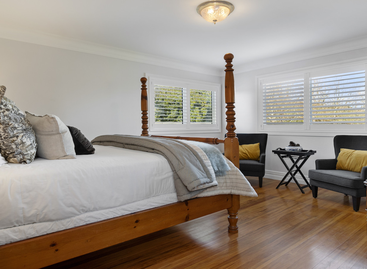 An elegant and rustic bedroom with a four-poster bed at Eagle Ridge, a luxury country lodge in Tauranga.