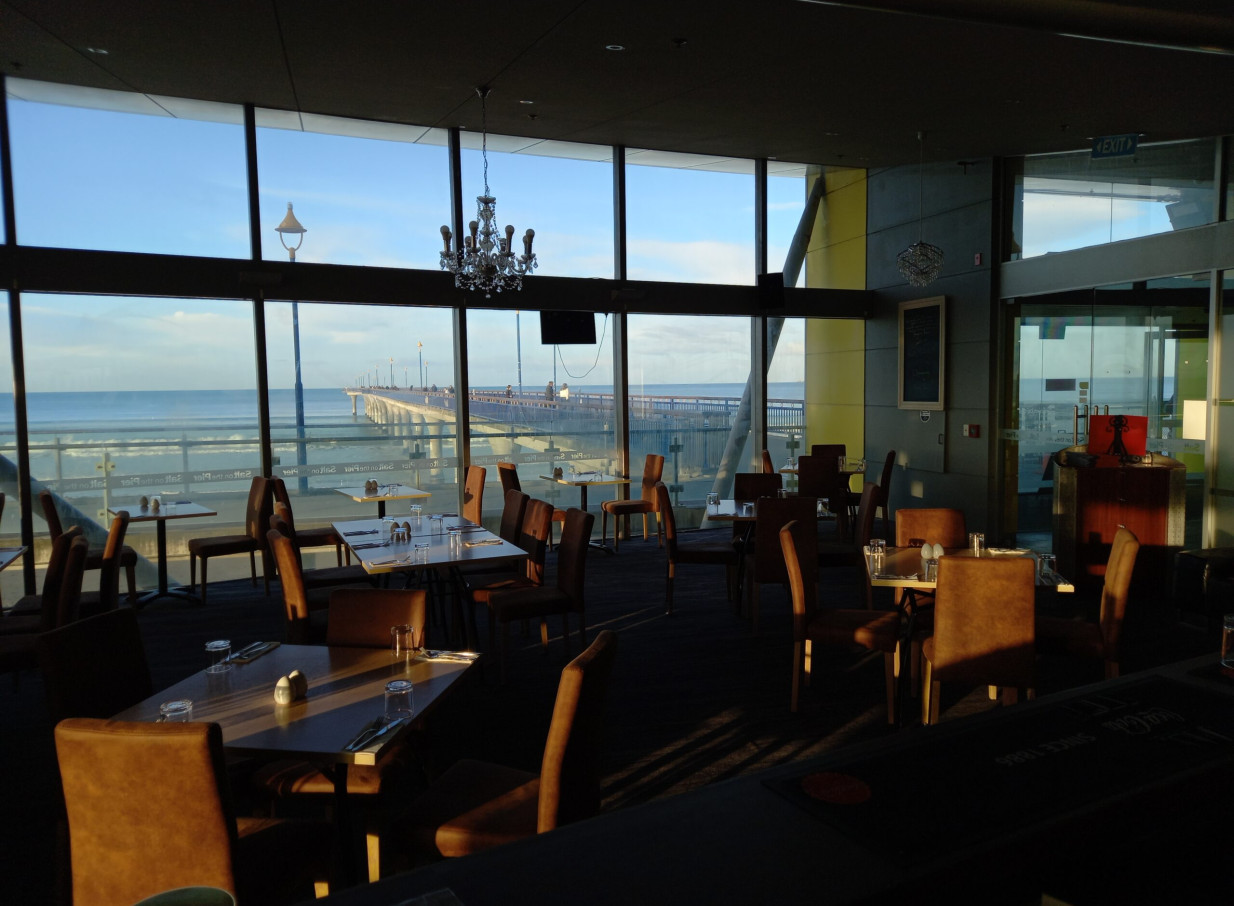 A modern dining room at Salt on the Pier in Christchurch, offering panoramic ocean and pier views.