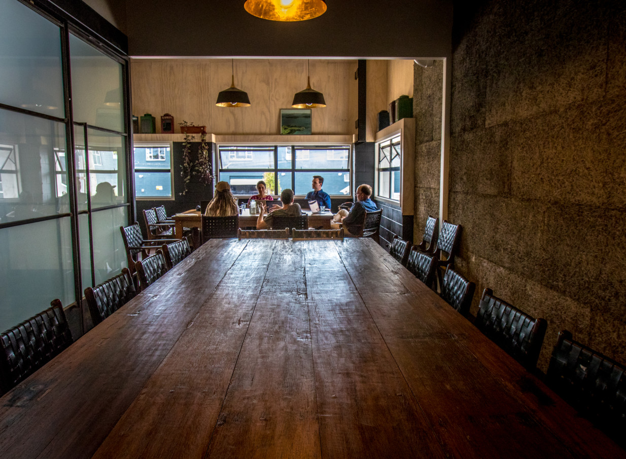 A long rustic wooden table in a private meeting area, reflecting Crave Cafe Auckland's industrial-chic style.