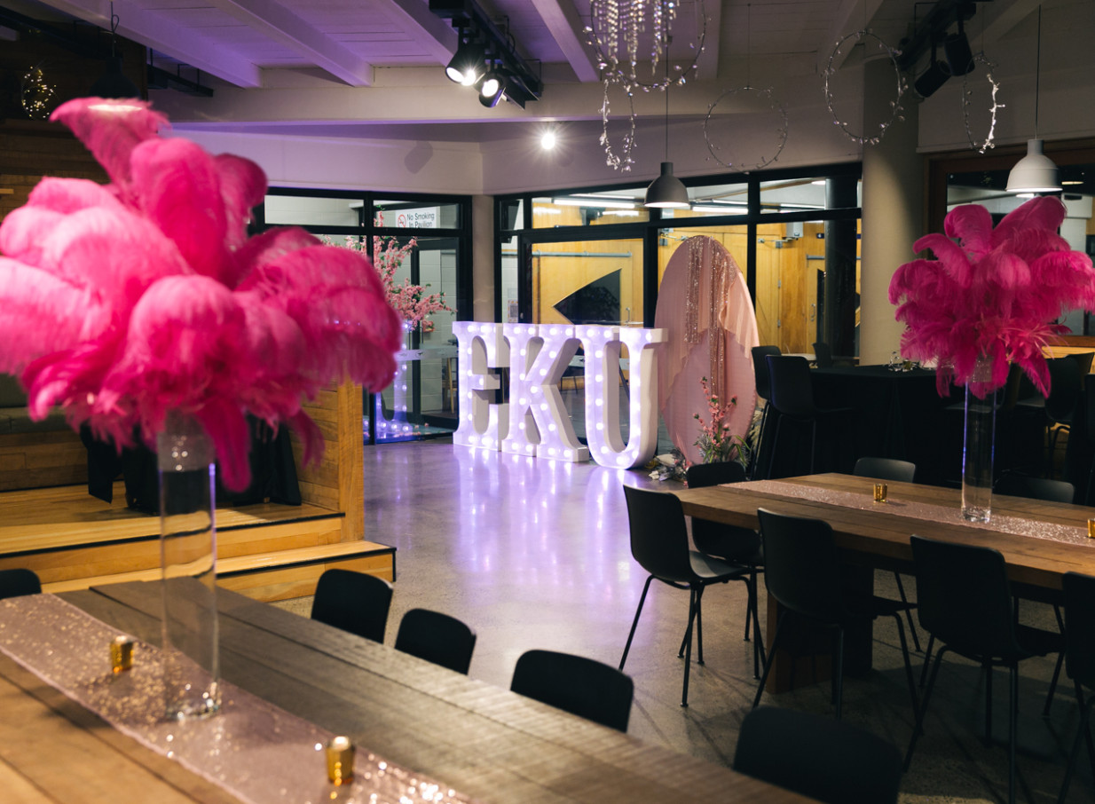 The versatile event space at Karaka Pavilion, Auckland, decorated for a celebration with pink feathers and illuminated letters.