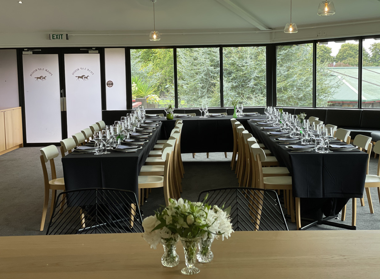 The modern Phar Lap Room at Karaka Pavilion, Auckland, set for a private dining event with tables overlooking lush gardens.