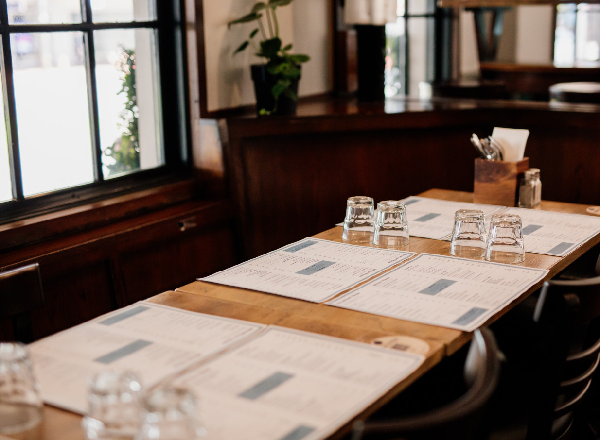 A classic Kiwi pub dining room at The Old Bailey in Wellington, with wooden tables set for guests.