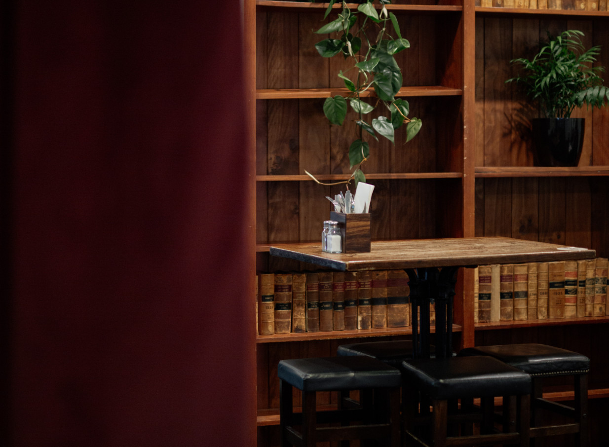 A cozy dining corner with a wooden table and bookshelf, reflecting the traditional Kiwi pub style of The Old Bailey, Wellington.