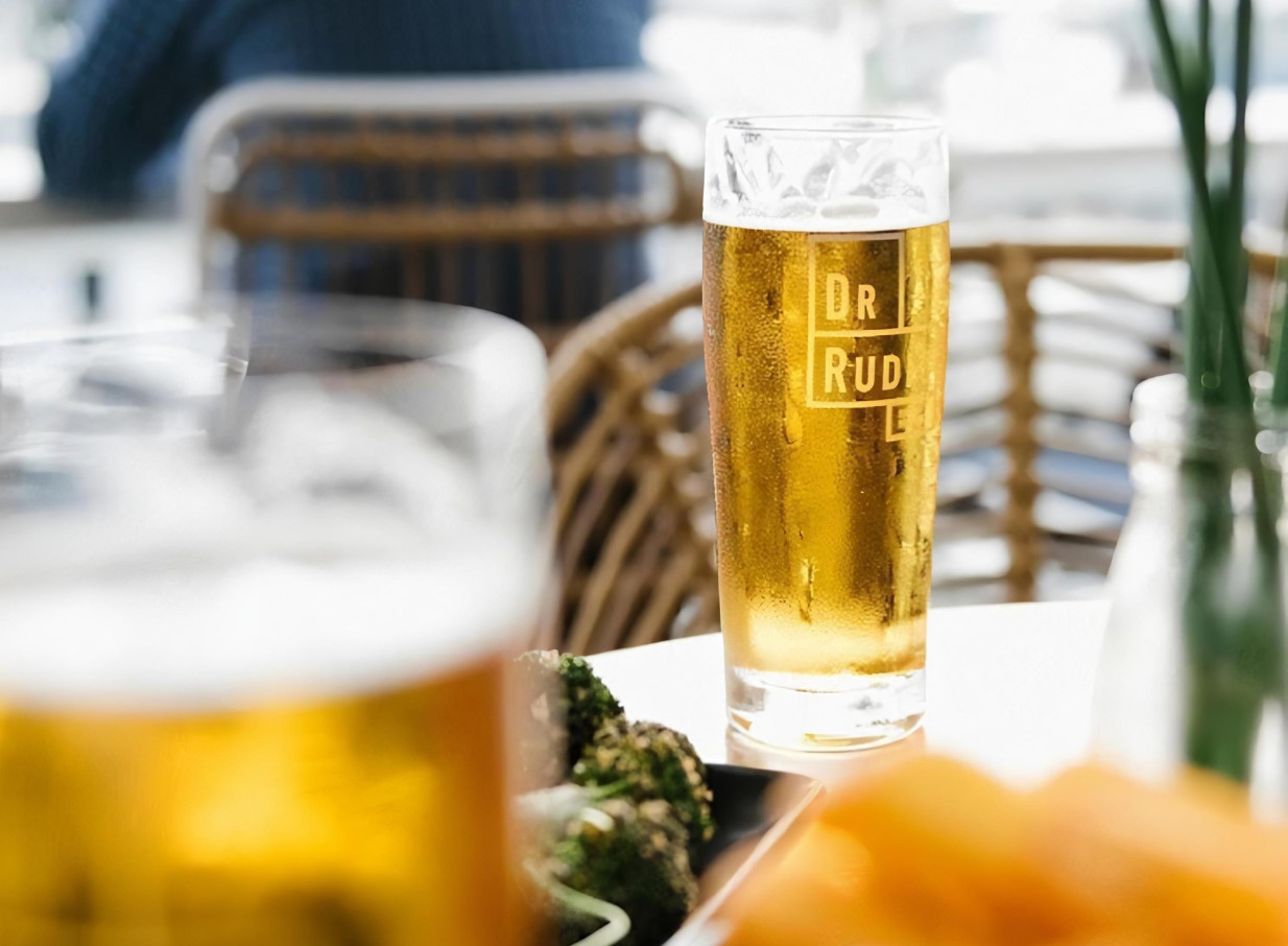 Enjoying a cold beer at Dr Rudi's, a vibrant rooftop bar overlooking Auckland's Viaduct Harbour.