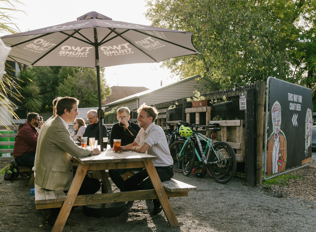 Patrons enjoy drinks on the laid-back outdoor patio of Two Thumb on Manchester, a rustic craft brewery in Christchurch.