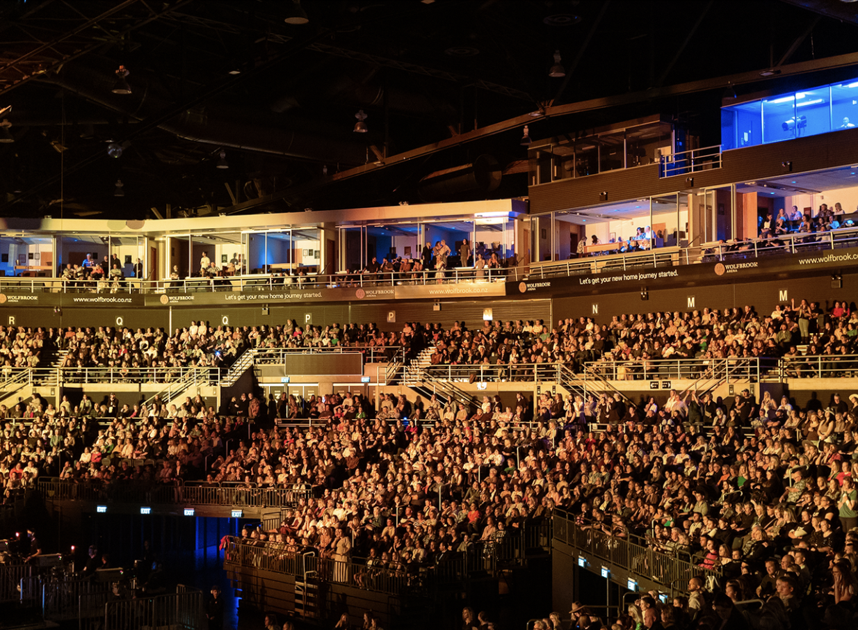 Wolfbrook Arena, a state-of-the-art indoor venue in Christchurch, filled with people in tiered seating and upper-level private boxes.