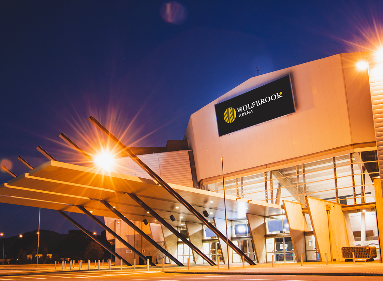 Night view of Wolfbrook Arena in Christchurch, showcasing its brightly lit, modern architectural exterior.