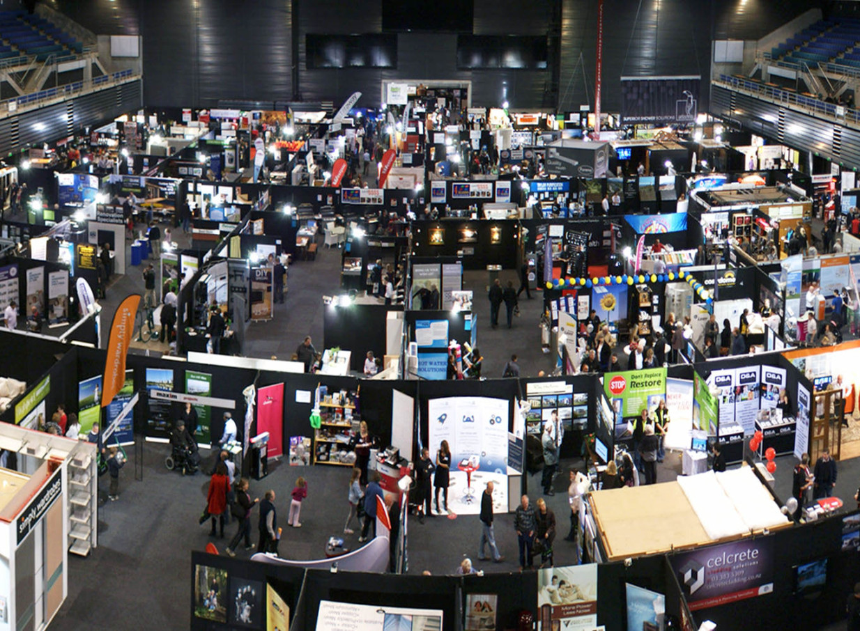 A vibrant indoor exhibition showcasing numerous booths and attendees fills the multi-purpose Wolfbrook Arena in Christchurch.