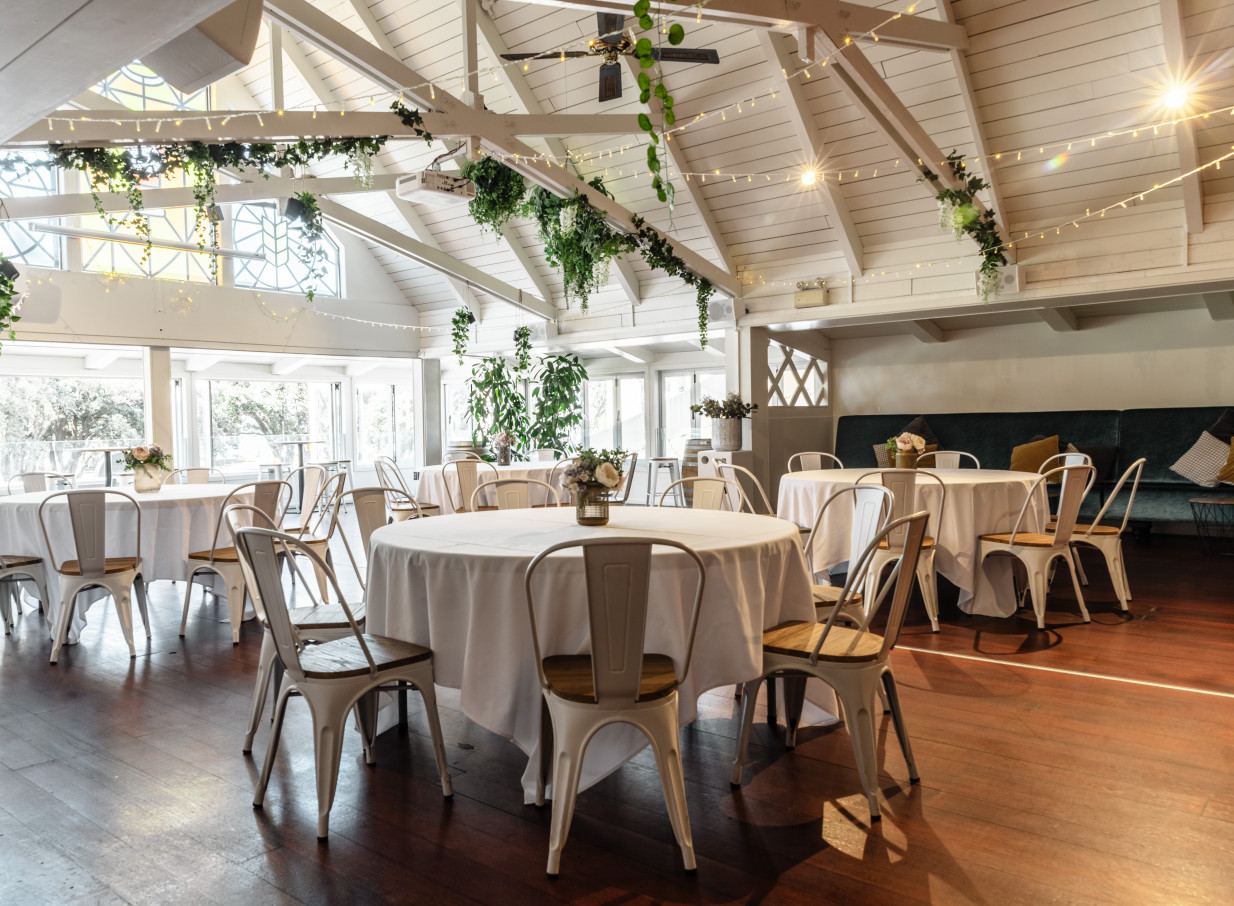 Mission Bay Taproom in Auckland offers a sophisticated event dining room with a high A-frame ceiling, decorated with fairy lights and greenery.