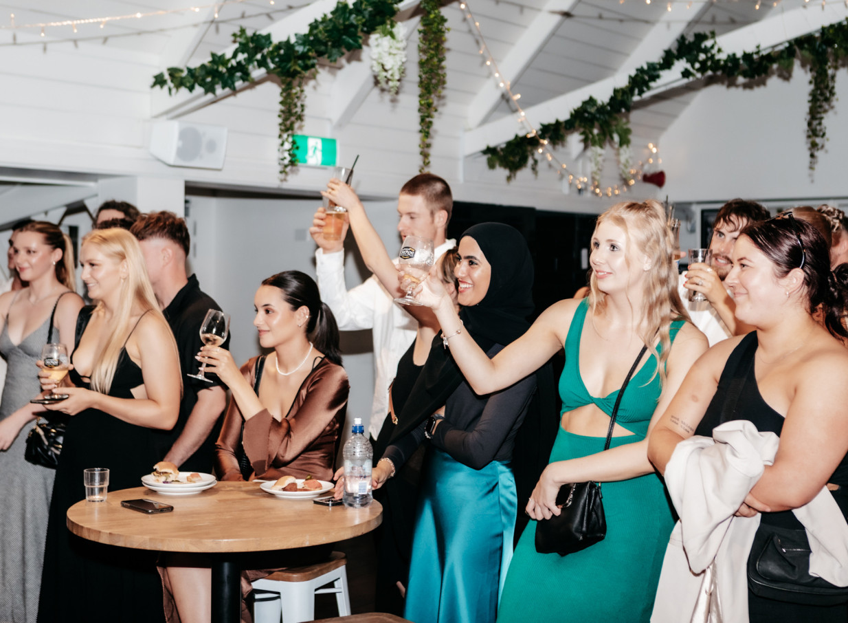 Guests raise glasses at a lively event in the modern Kiwi-styled function room of Mission Bay Taproom in Auckland.
