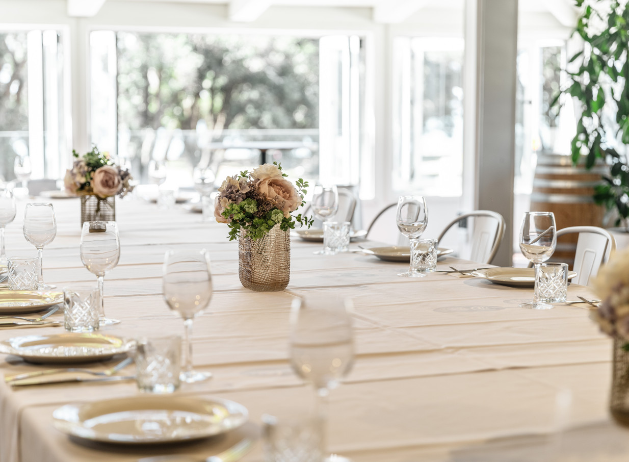 An airy, rustic-modern dining area at Mission Bay Taproom, Auckland, featuring set tables and large windows.