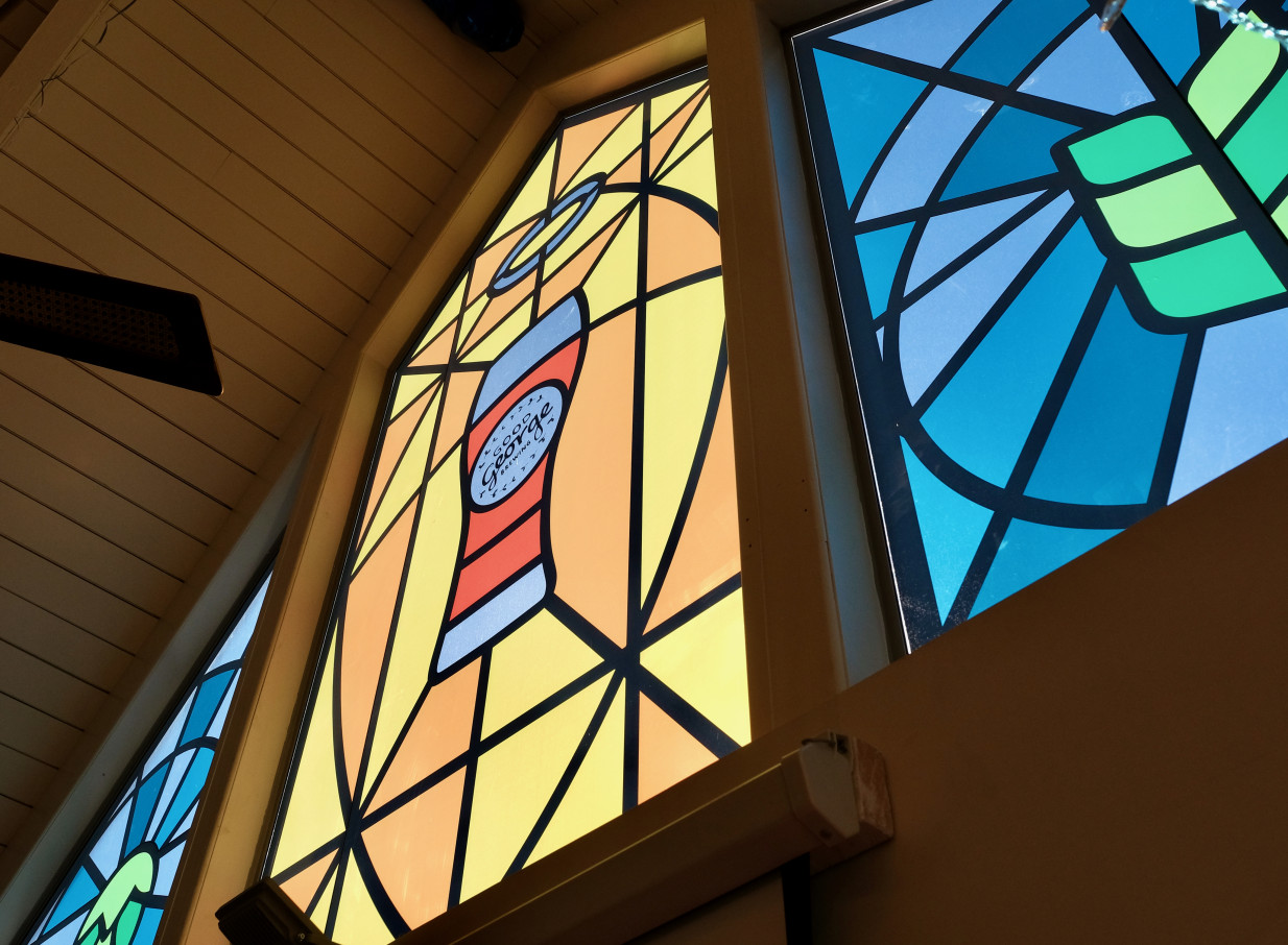 Vibrant stained-glass windows, part of the rustic-modern design with an A-frame ceiling, brighten Mission Bay Taproom, Auckland.