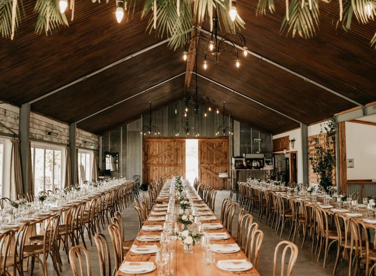 A rustic barn reception at Broadlands Lodge in Taupo, featuring long tables set for guests in a romantic country setting.