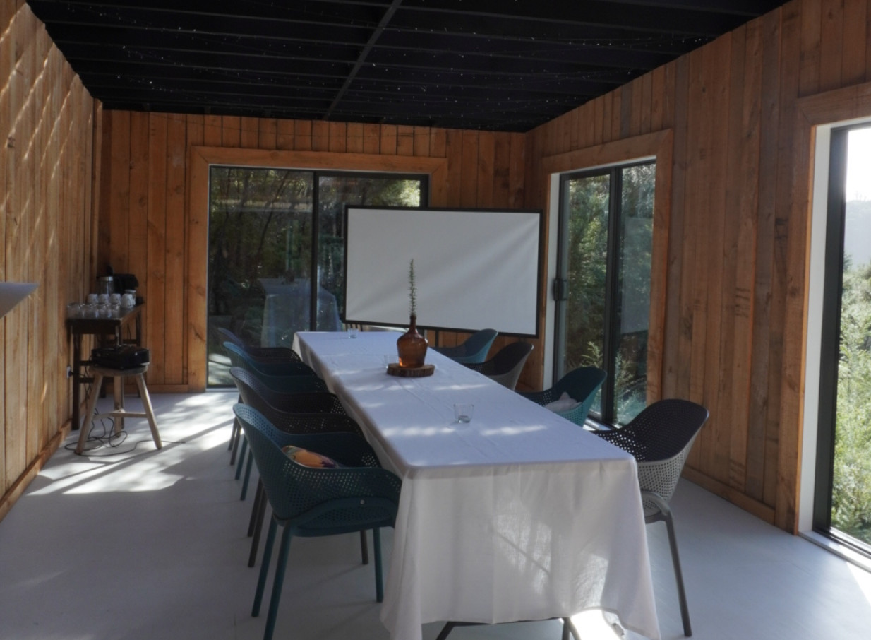 A Scandanavian-inspired meeting or private dining room at Parohe Island Retreat, Auckland, with wooden walls and lush bush views.