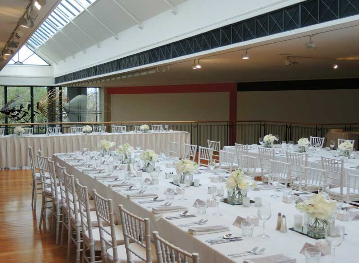 A formal dinner event set within the architecturally modern, glass-roofed atrium of the Dunedin Public Art Gallery in Dunedin.