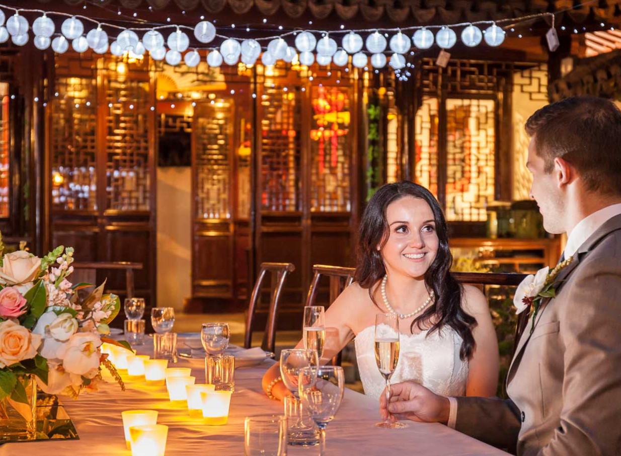 A couple enjoys an elegant reception amid the traditional Chinese garden architecture of the Dunedin Chinese Garden, Dunedin.